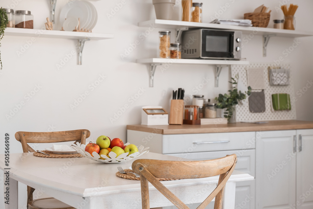 Interior of light kitchen with fruit basket on dining table Interior of light kitchen with fruit basket on dining table
