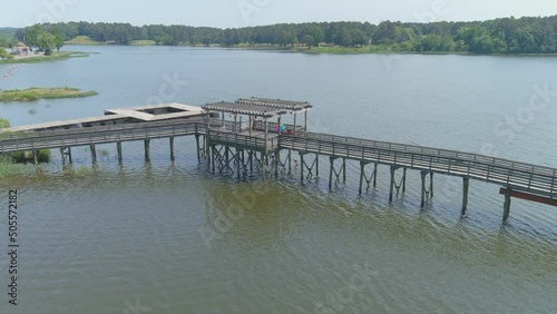 gorgeous aerial footage of brown wooden bridge and a brown wooden dock on a rippling green lake surrounded by lush green trees, grass and plants at Cauble Park at Lake Acworth in Acworth Georgia USA photo