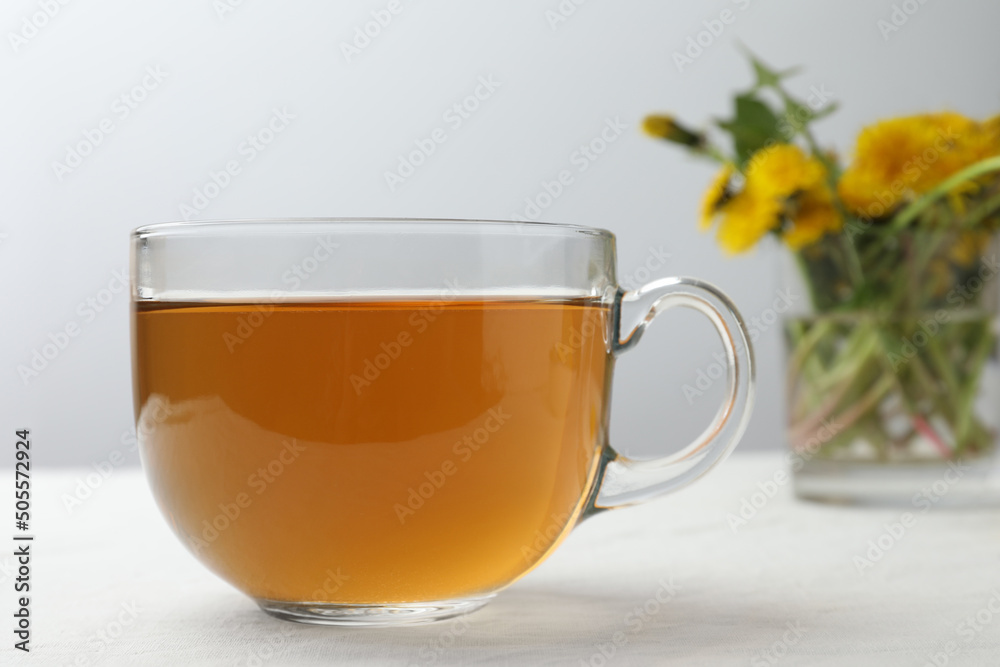 Delicious fresh tea and beautiful dandelion flowers on white table Delicious fresh tea and beautiful dandelion flowers on white table