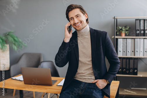 Handsome businessman in suit talking on the phone in the modern office