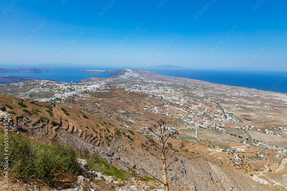 Panoramic wide angle view over the most popular island in the cyclades archipelago, Santorini, Greece. Blue Aegean Sea on the horizon, white houses in between dry brown landscape. Aerial view