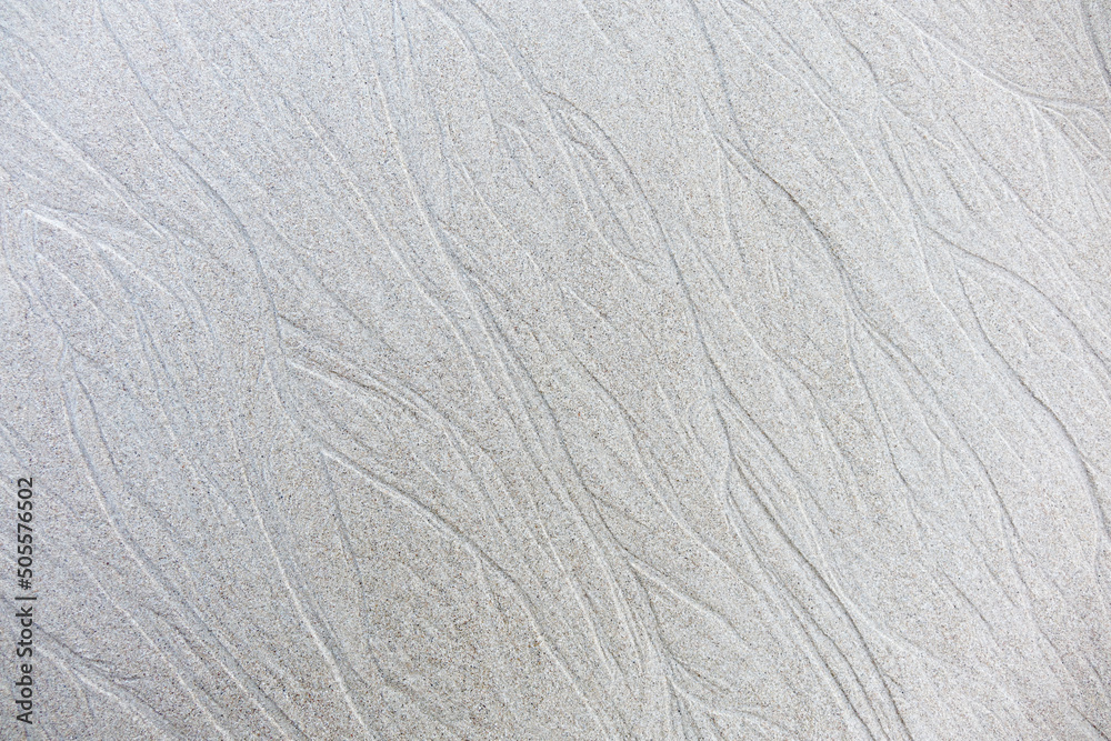 Sand background and texture. Wet beach sand texture after low tide. Sand with wave print. Ripple on the beach sand. Sand background and texture. Wet beach sand texture after low tide. Sand with wave print. Ripple on the beach sand.