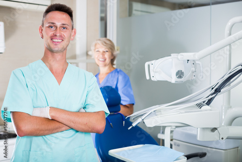 Male dentist standing in dental office with hands crossed looking at camera