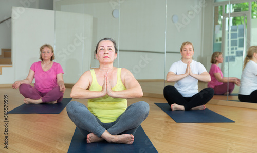 Mature woman making yoga meditation in half king of fish yoga pose - agni stambhasana photo