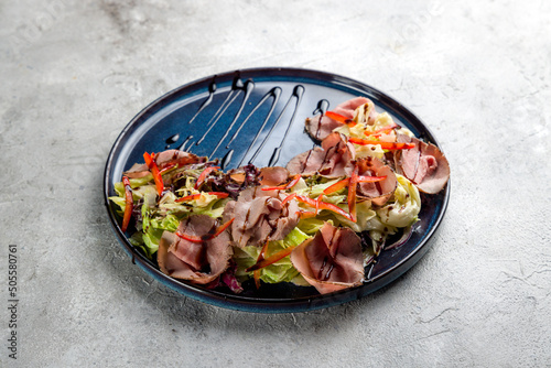 Salad with roast beef and vegetables on blue plate