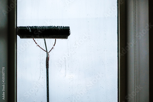 Window cleaning using telescopic water brush and wash system. Commercial window cleaning from the outside with sky in background. Defocused