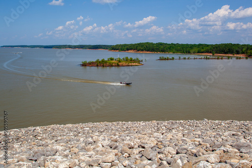  Sardis Dam and reservoir lake on the Tallahatchie River at John W Kyle State Park in Panola County, Mississippi. With Boats, partly cloudy sky, green grass, and the Sardis Lake Marina.