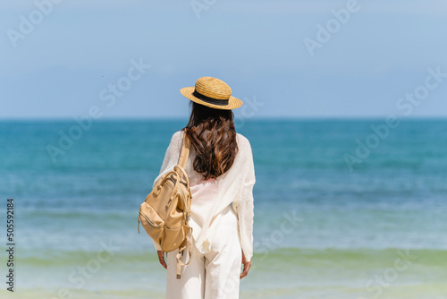 Woman wearing straw hat with bag standing on beach