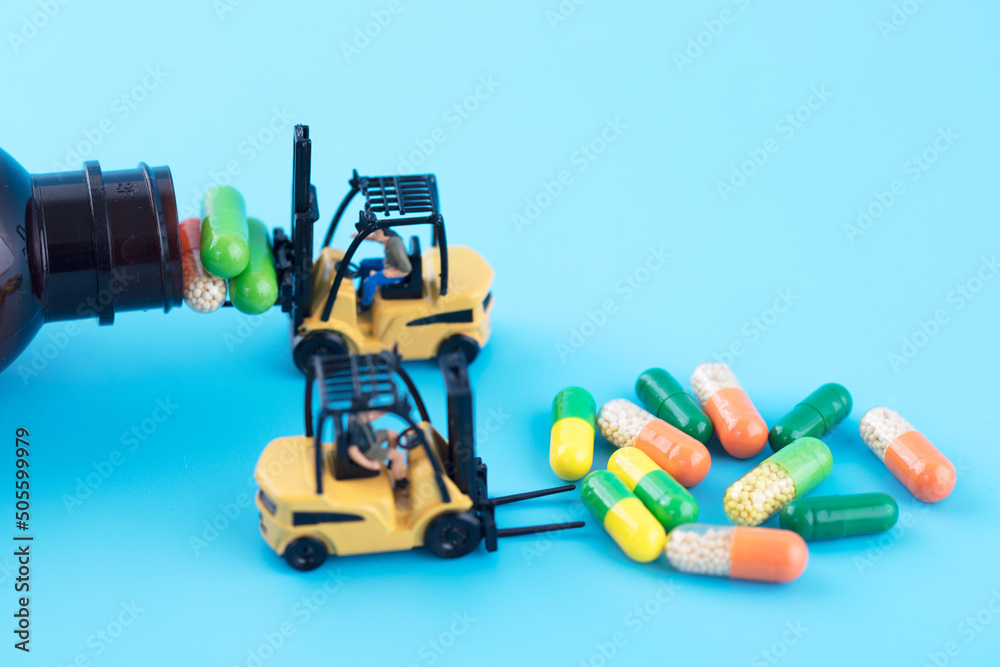Fototapeta premium Miniature creative forklift loads capsules into medicine bottles