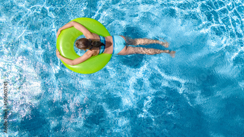 Active young girl in swimming pool aerial drone view from above  teenager relaxes and swims on inflatable ring donut and has fun in water on family vacation  tropical holiday resort