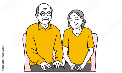 笑顔で椅子に座る高齢者の夫婦	