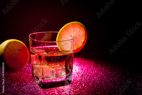 Glass transparent glass with drink and ice cubes for cooling and lemon.