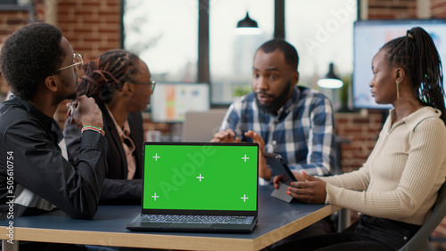 Businesspeople attending briefing meeting with greenscreen on laptop, using blank copy space with isolated chroma key background and mockup template. Modern technology in startup office.
