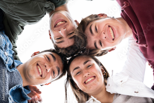 Low angle view of cheerful teenager group looking down at camera.