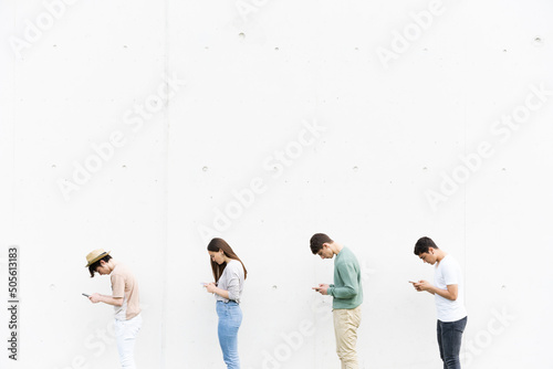 Queue of teenagers using their phones in bad posture. Lordosis and kyphosis on young people concept.