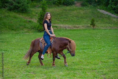 girl riding a pony on a green lawn © zokov_111