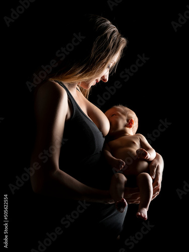 Young mother in the studio breastfeeding her newborn baby