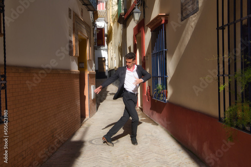 flamenco and gipsy man, dressed in black and white shirt and red polka dots handkerchief dancing flamenco in an alley in the streets of a mediterranean city. Flamenco cultural heritage of humanity.