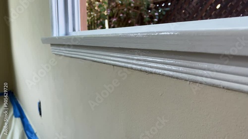 Male Hand Painting Trim of Window with White Paint, Close Up of Paint Brush on Edge of Window photo