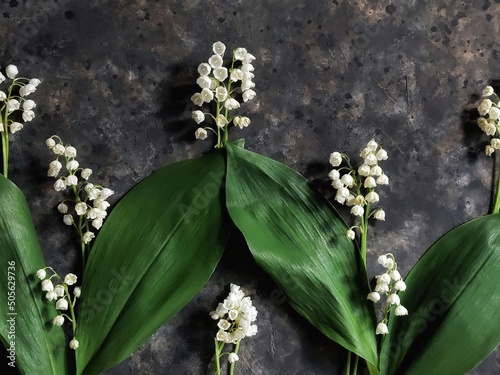 Creative pattern of lilies of the valley flowers. Flatlay with spring flowers on black concrete background.