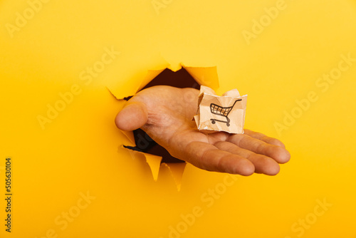 Male hand with a small broken delivery box through a yellow paper hole. Delivery service mistake