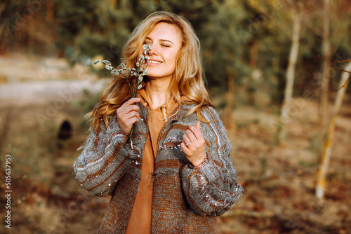 Portrait of young happy gorgeous woman standing in spring forest, holding bunch of pussy-willow, sniffing, enjoying. photo