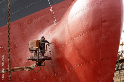 Fotografiet Workers working in a shipyard and painting in naval industry