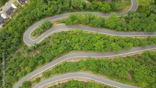 Cars driving up a long curvy switchback road in west Germany. Ascending high angle drone footage photo