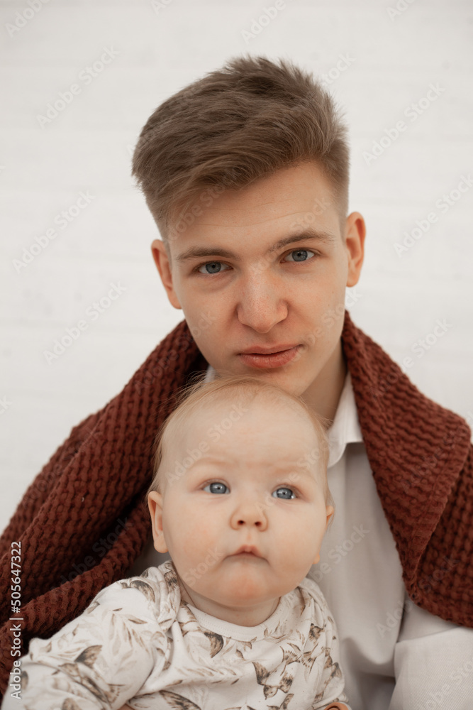 Φωτογραφία Portrait of young tired father dad covered with brown plaid holding little cute plump grey-eyed baby infant toddler