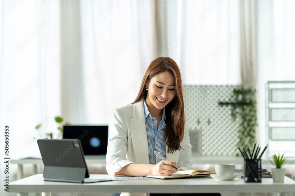 Beautiful young Asian girl working at a office space with a laptop. Concept of smart female business.