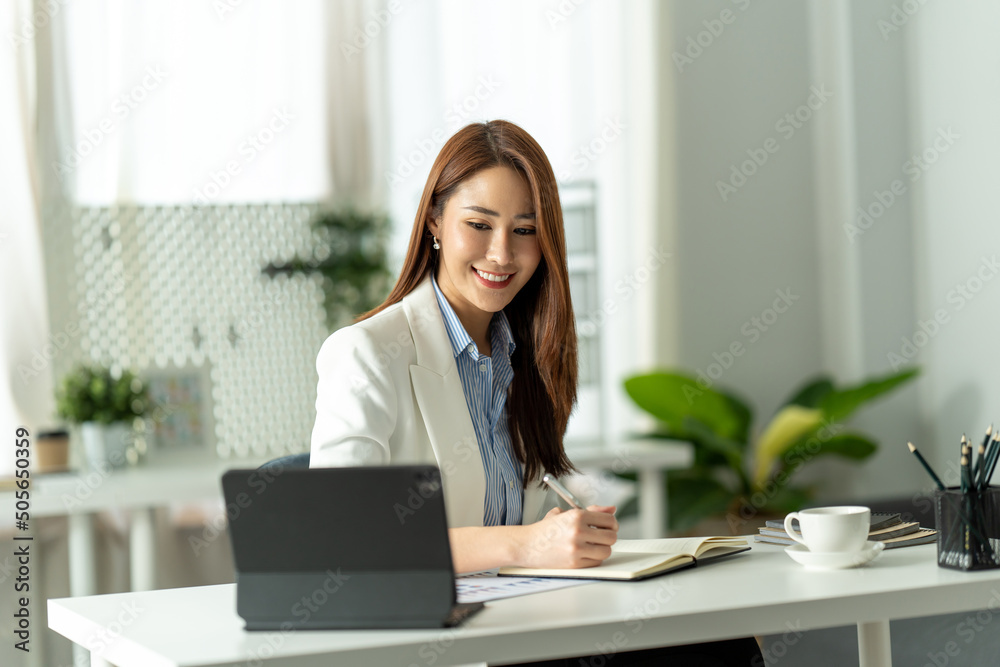 Attractive young brunette asian woman using laptop computer while sitting in a stylish living room. Attractive young brunette asian woman using laptop computer while sitting in a stylish living room.