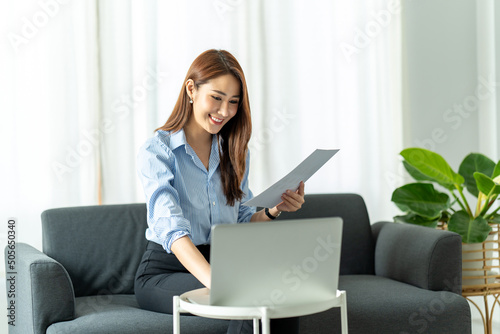 woman using laptop in the sofa with a happy face sitting and smiling with a confident smile. © PaeGAG