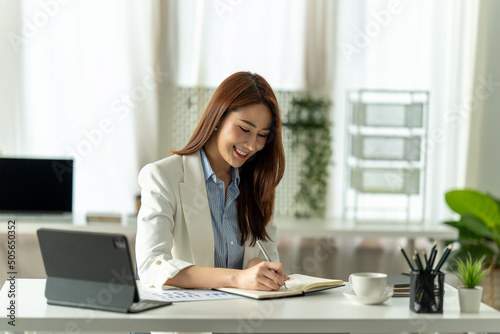 Attractive young brunette asian woman using laptop computer while sitting in a stylish living room.