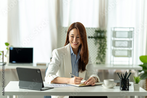 Attractive young brunette asian woman using laptop computer while sitting in a stylish living room.