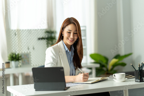 Attractive young brunette asian woman using laptop computer while sitting in a stylish living room.