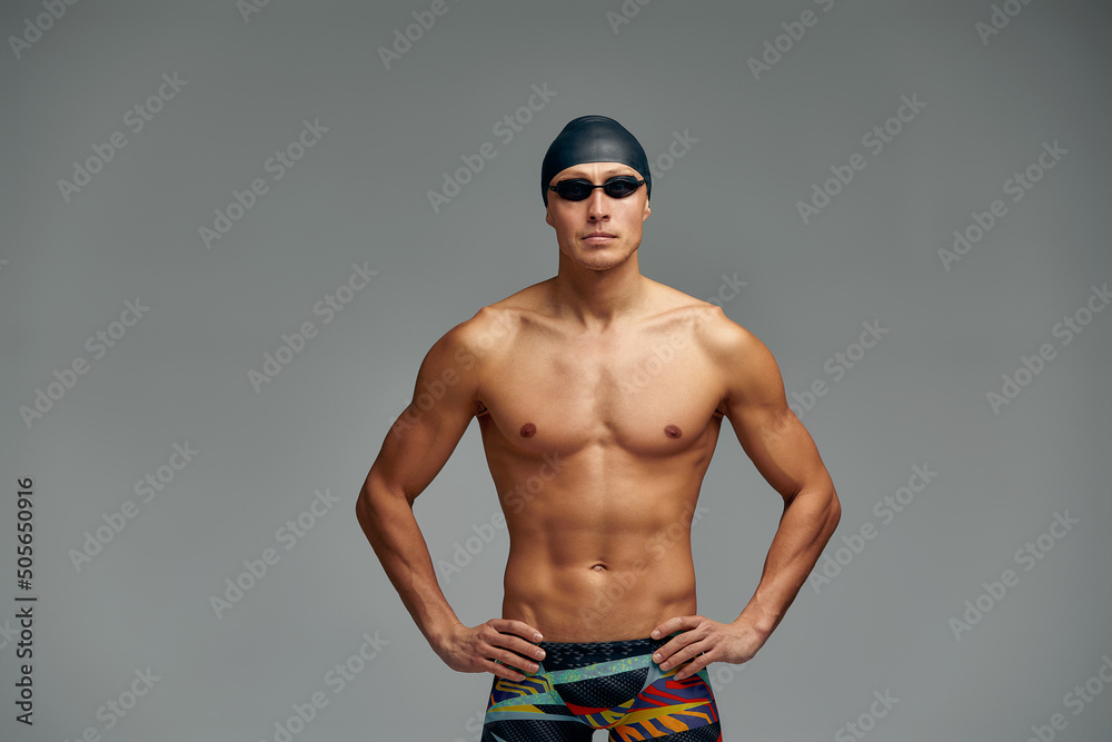 Portrait of a swimmer in a cap and mask, half-length portrait, young athlete swimmer wearing a cap and mask for swimming, copies of space, gray background.