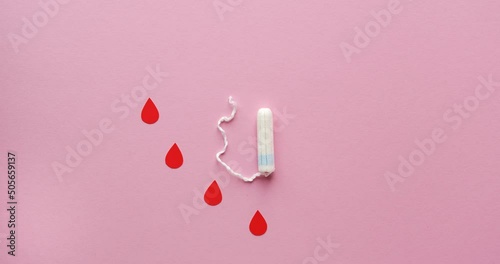 Women's tampon and drops of blood cut out of paper in a shape of heart. Menstrual cycle. Looped 4K stop motion animation on pink background photo