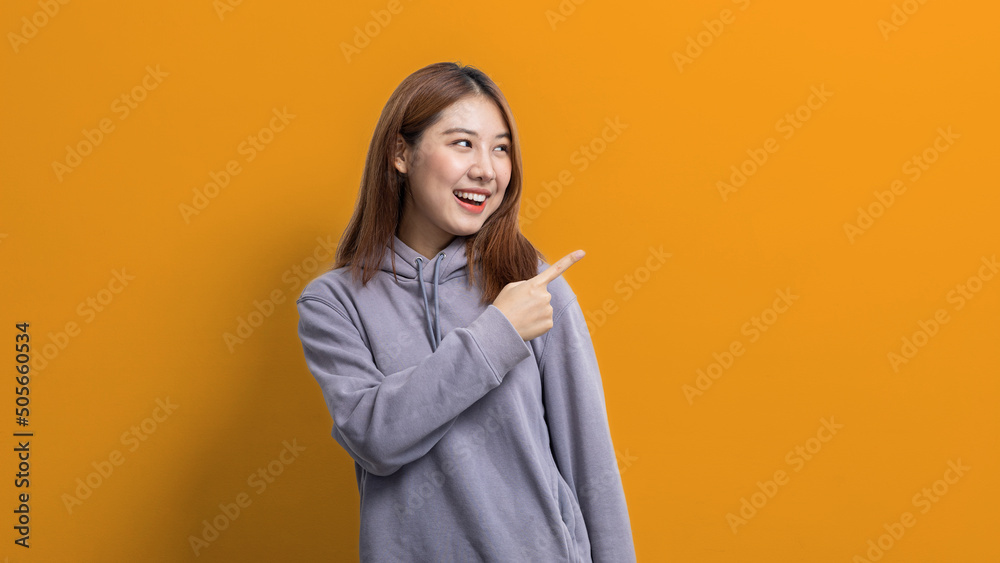 Portrait of Asian woman gesturing pointing at empty space for ad text, portrait concept used for advertisement and signage, isolated over yellow background, copy space. Portrait of Asian woman gesturing pointing at empty space for ad text, portrait concept used for advertisement and signage, isolated over yellow background, copy space.