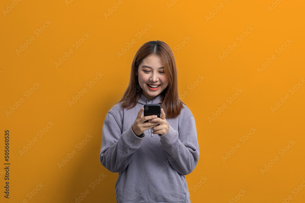 Portrait of beautiful Asian woman holding mobile phone on isolated background, portrait concept used for advertisement and signage, isolated over yellow background, copy space. Portrait of beautiful Asian woman holding mobile phone on isolated background, portrait concept used for advertisement and signage, isolated over yellow background, copy space.