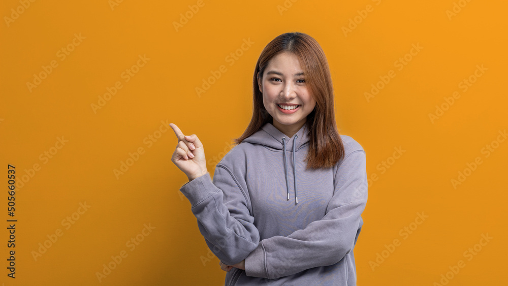 Portrait of Asian woman gesturing pointing at empty space for ad text, portrait concept used for advertisement and signage, isolated over yellow background, copy space. Portrait of Asian woman gesturing pointing at empty space for ad text, portrait concept used for advertisement and signage, isolated over yellow background, copy space.