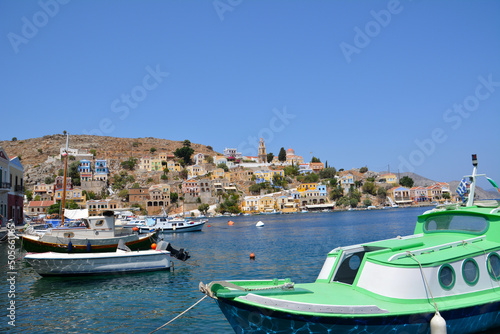 greek island with colored boats and houses on blue sky background
