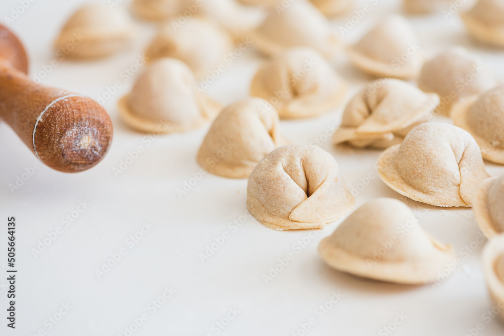 Uncooked homemade pelmeni on white table. Process of making pelmeni, ravioli or dumplings with meat Uncooked homemade pelmeni on white table. Process of making pelmeni, ravioli or dumplings with meat