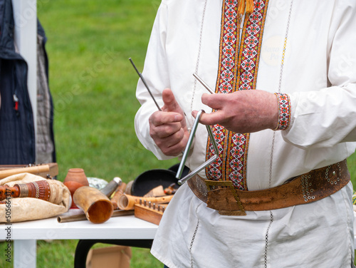 Musician man plying triangle striking beater. Ukraininan idiophone metal ethnic musical instrument. Folk music festival photo