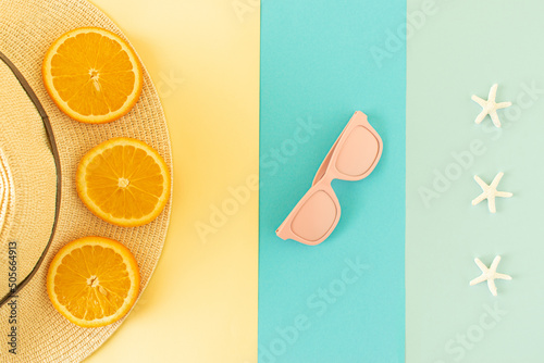 Sunhat with orance slice, pink sunglasses and starfish on pastel background. Summer beach and fruit wallpaper. photo