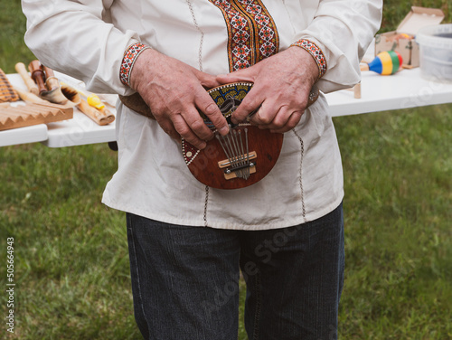 Musician plying mbira ethnic musical instrument. Ukraininan kalimba, finger harp, gourd piano, ikembe. Classification Lamellophone, Plucked Idiophone. Folk music festival Lviv, Ukraine photo