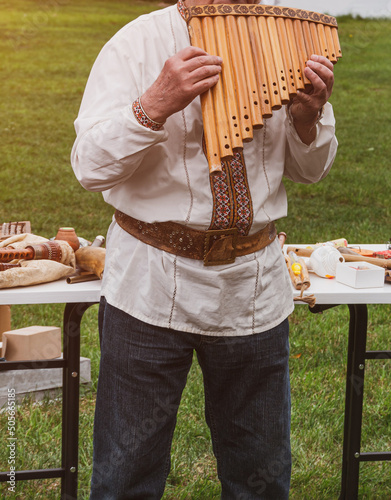 Musician man in vyshyvanka plying sopilka rebro ethnic woodwind musical instrument. Pan flute, panpipes syrinx, multiple pipes of gradually increasing length. Ukraininan folk music festival in Ukraine photo