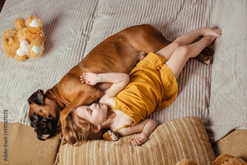 Canvas Print little girl at home on the couch goes to bed with her big dog, trust and friends