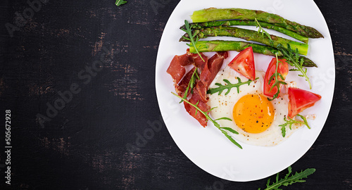 Fried egg with asparagus, tomato and bacon. Useful breakfast. Top view, overhead