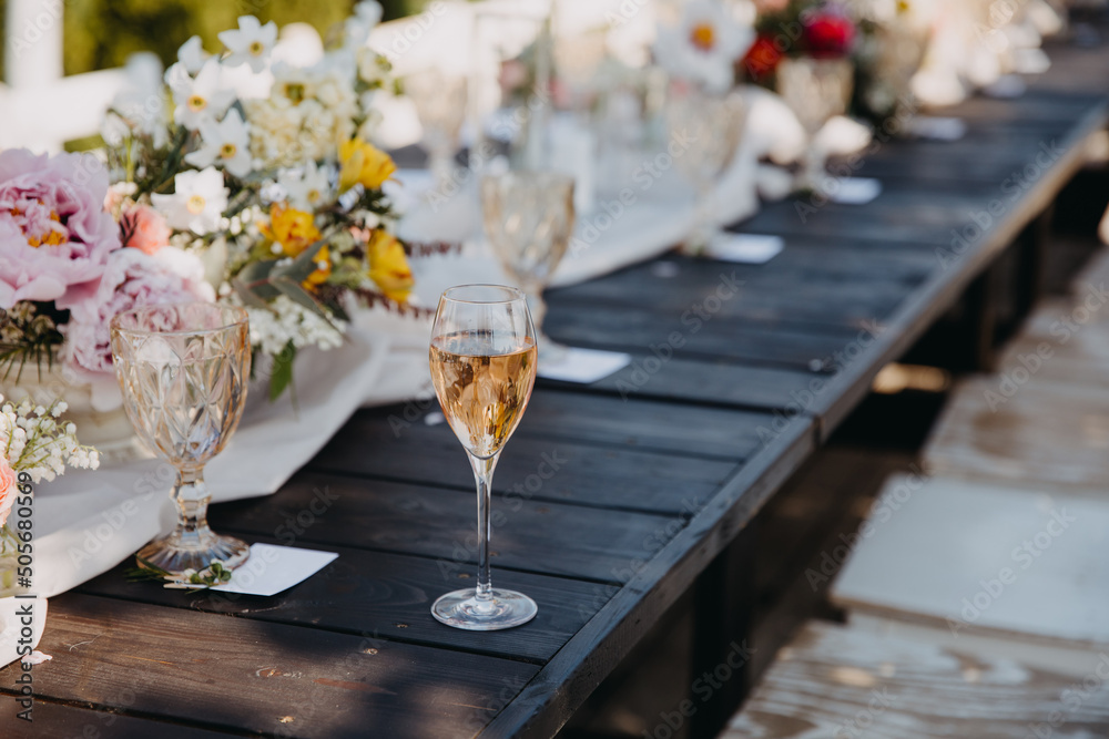 glass of champagne on a wooden table at an open air party. glass of champagne on a wooden table at an open air party.