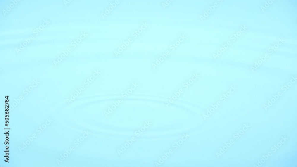 Side view slow motion scene of waterdrop dropping on a surface of water isolated on blue background, raindrop falling down to the ground, clean drink concept, science wavelength experiment laboratory Side view slow motion scene of waterdrop dropping on a surface of water isolated on blue background, raindrop falling down to the ground, clean drink concept, science wavelength experiment laboratory